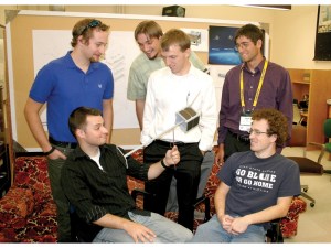Clockwise from lower left, GAS team coordinator James Gardiner displays a model of a USU-designed cube satellite with inflatable boom to team members Trevor Kunz KF7YZY, Jorden Luke KF7YEM, Jeremiah Christensen, Micah Fry and Troy Munro KE7URC